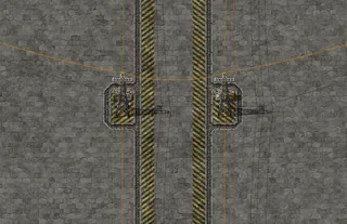Detalhe da rua entre dois blocos: as bases dos postes da borda ficam frente a frente, uma espelhando a outra, com as faixas de perigo dos dois lados e um fio de cobre cruzando a rua, capturado no jogo